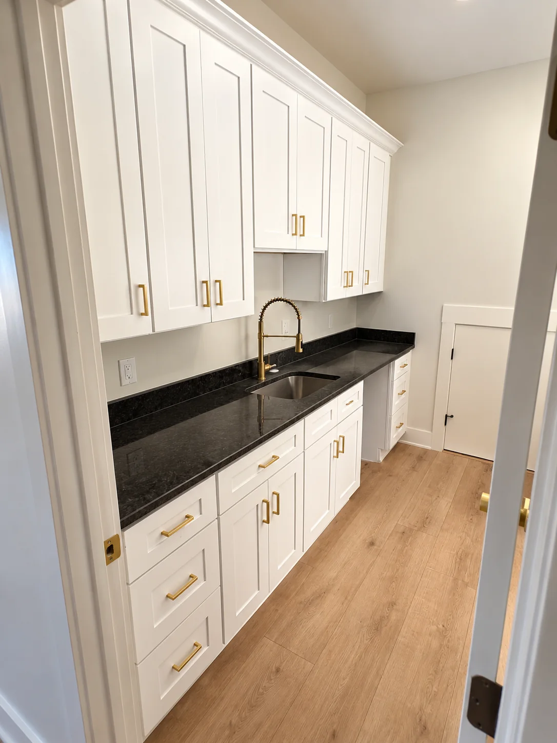Fox Hill utility room with white cabinets, a dark countertop, and a brass faucet