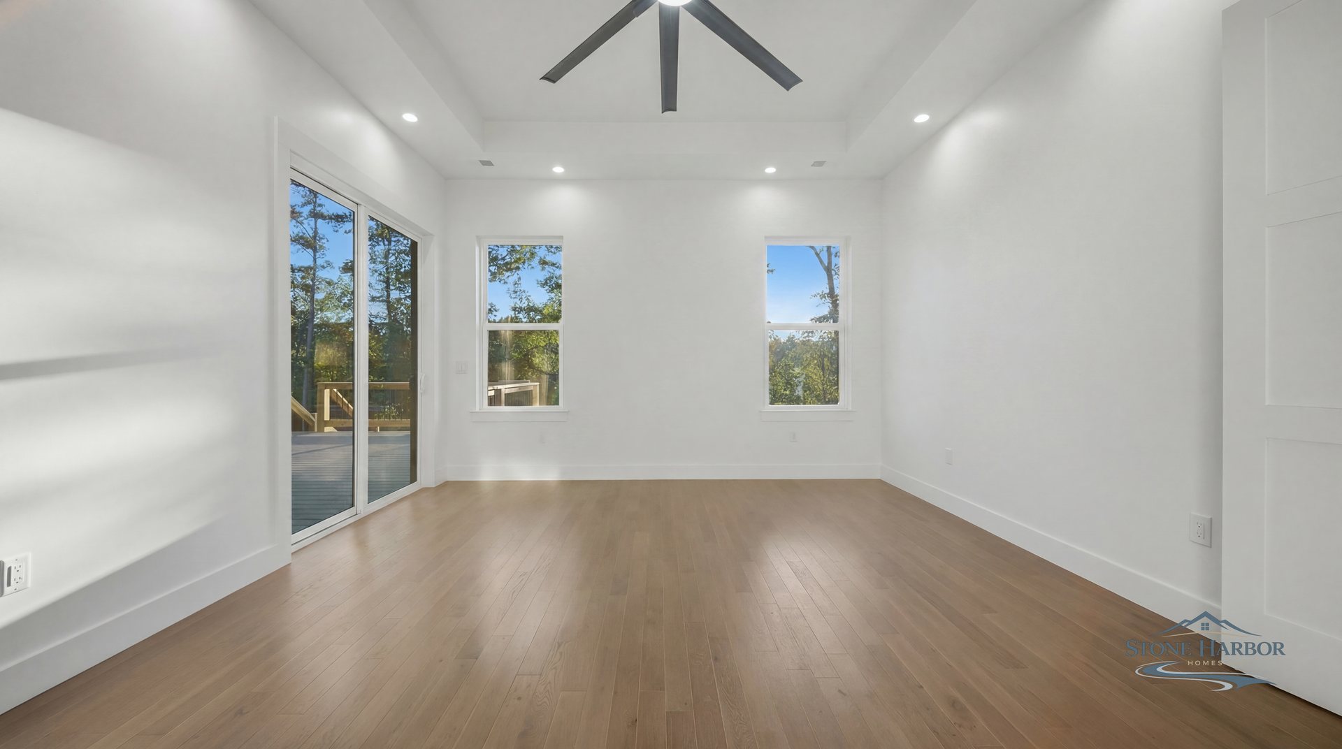 Bedroom with a vaulted ceiling, ceiling fan, and sliding-door access to the deck