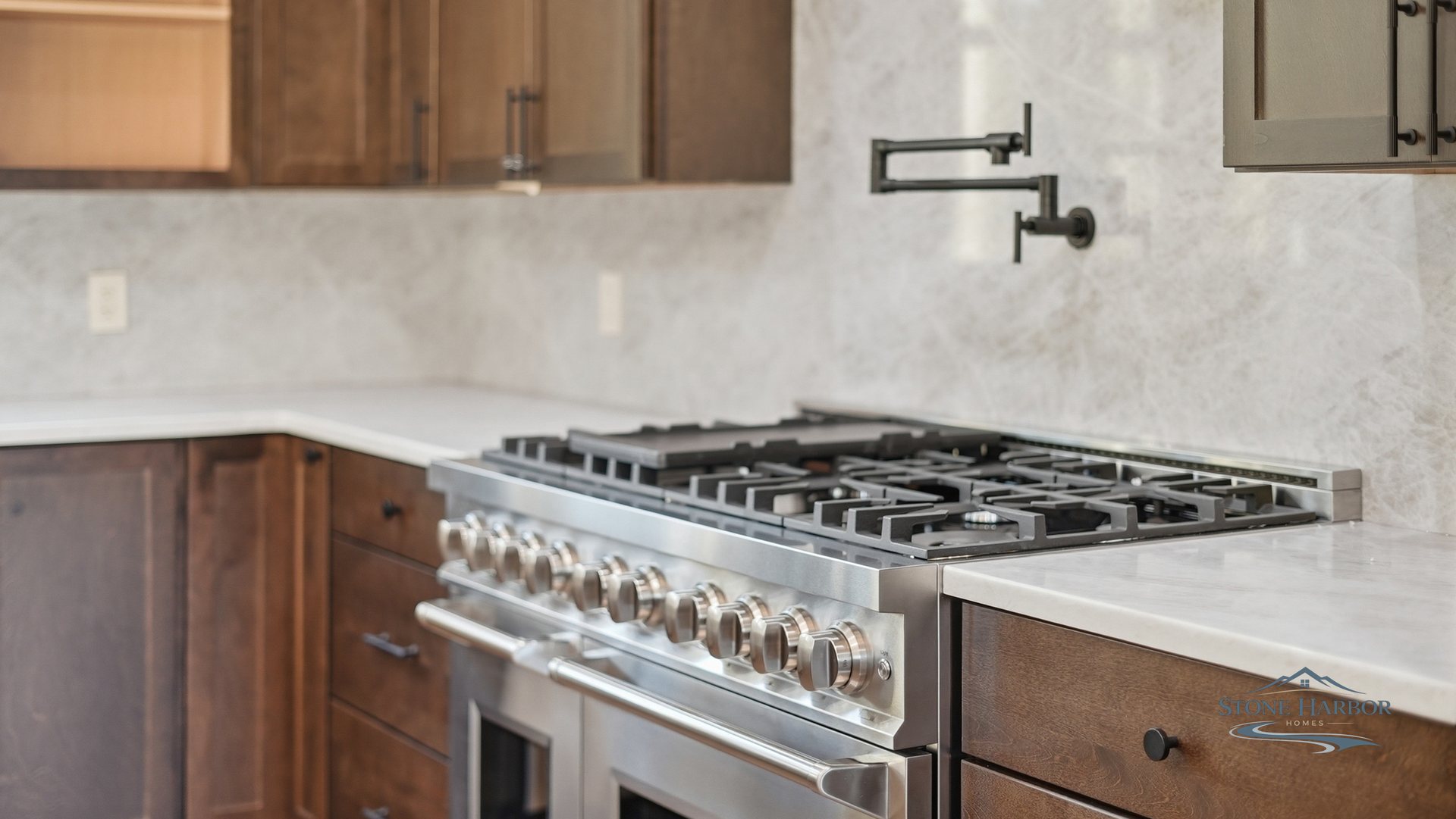 Kitchen detail with a professional gas range, marble subway backsplash, and a pot filler