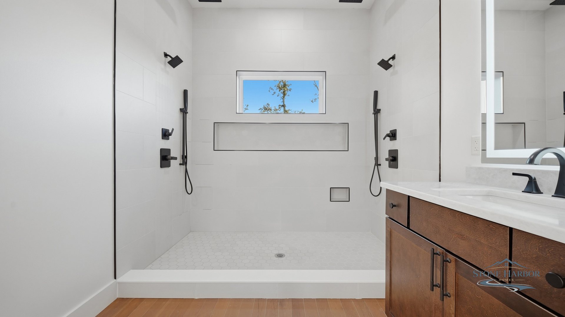 Primary bath with a tiled walk-in shower, built-in bench, and a wood vanity with marble counter
