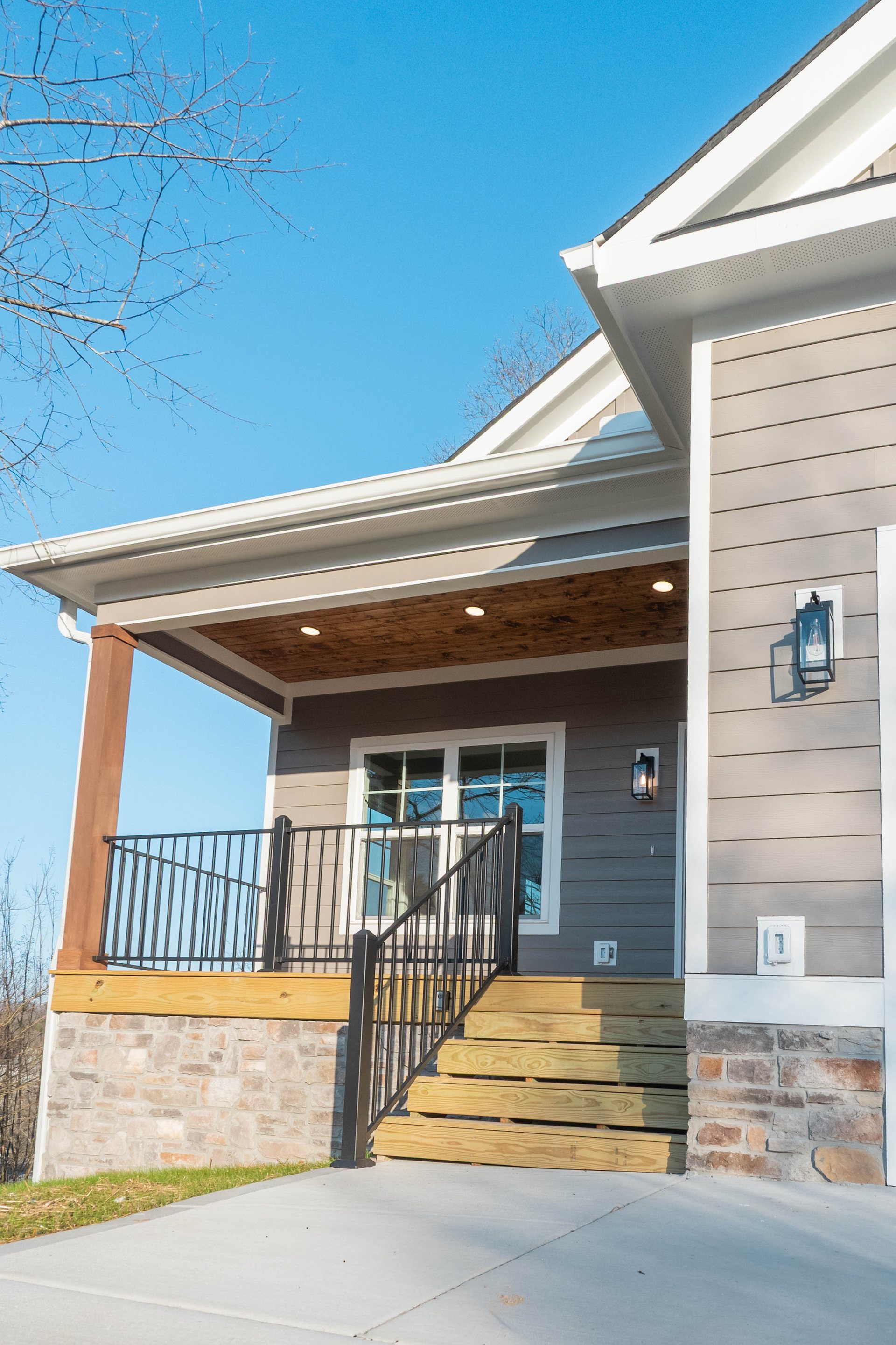 Lightning Drive covered front porch with stone-wrapped columns and railings