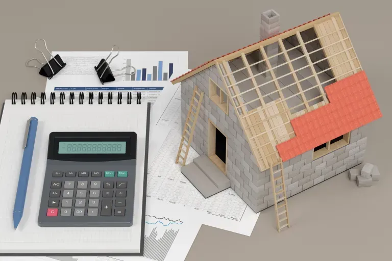 Calculator next to a model of a house under construction